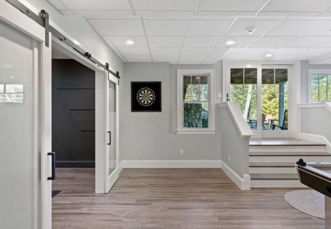 Finished basement with sliding barn doors, dart corner, and steps to outdoor patio (JM Construction)
