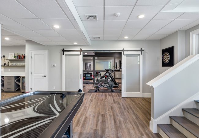 Finished basement with pool table, open floor plan, and sliding barn-style doors (JM Construction)