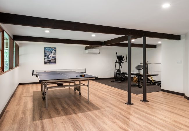 Finished basement with open floor plan, ping pong table, and workout area (JM Construction)