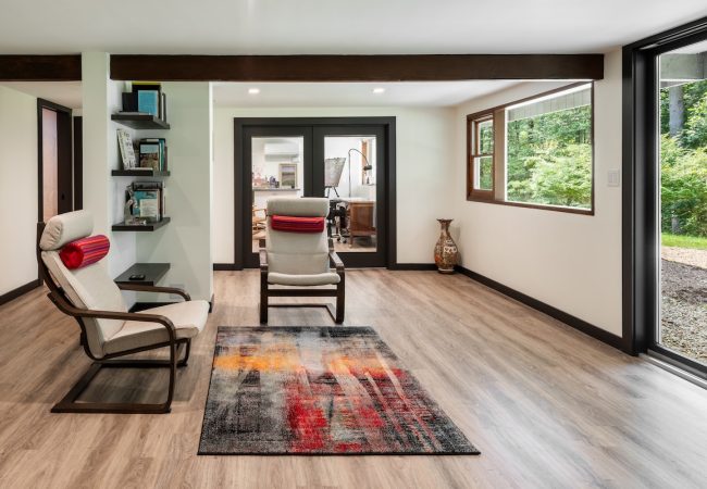 Finished basement sitting area with built-in wall shelves and sliding glass patio door (JM Construction)