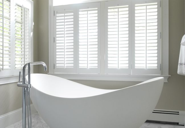 Large freestanding tub with arched window bringing in natural light (JM Construction)