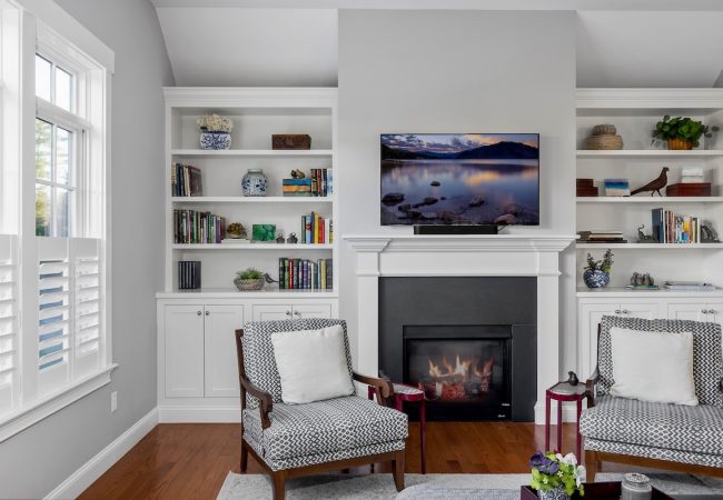Home addition sitting room with fireplace, built-in shelves, custom finishes, and large windows (JM Construction)