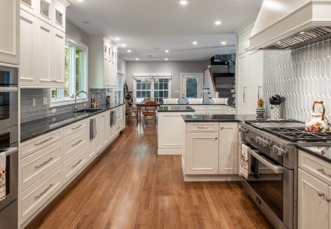 Updated kitchen with wood floors, island, custom tile backsplash, built-in cabinets, and open floor plan (JM Construction)