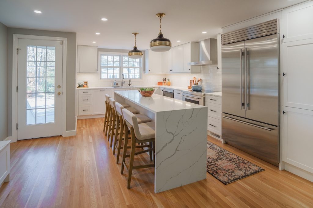 Updated kitchen with large sit-down island, double-door fridge, wood floors, and steps to backyard (JM Construction)