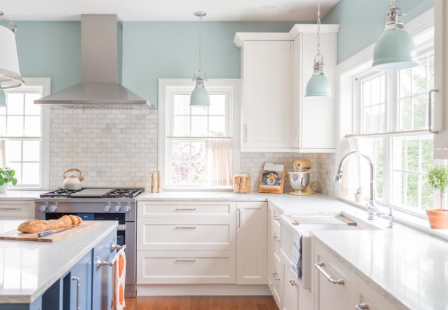 Updated kitchen with island, bright windows, ceiling hood, white granite countertops, and white cabinets (JM Construction)