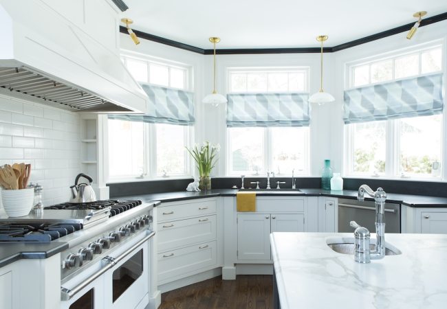 Updated kitchen with island prep sink, large cooktop and hood, and three windows for natural light (JM Construction)