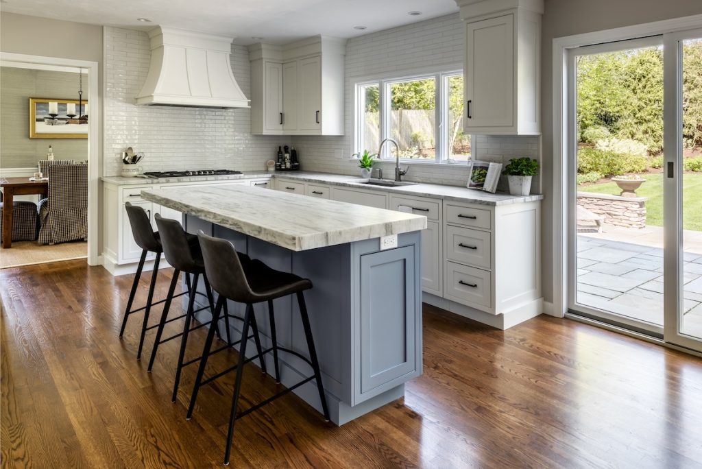 Updated kitchen with large sit-down island, sliding glass door to deck, open floor plan, and tile backsplash (JM Construction)