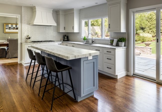 Updated kitchen with large sit-down island, sliding glass door to deck, open floor plan, and tile backsplash (JM Construction)