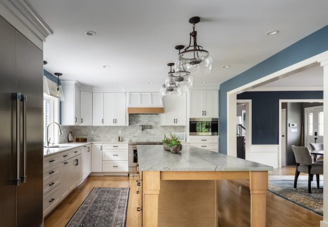 Updated kitchen with large sit-down island, wraparound cabinets, dining area, and tall fridge (JM Construction)