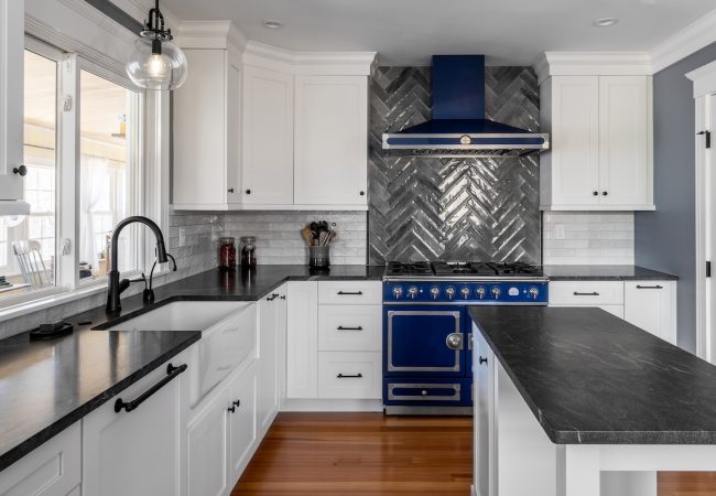 Updated kitchen with island, custom tile backsplash, built-in cabinets, farmhouse sink, and windows above sink (JM Construction)