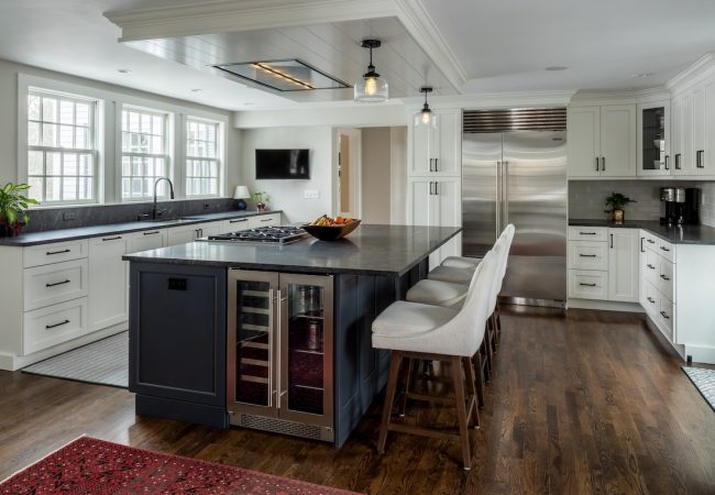 Updated kitchen with large island, built-in mini fridge and cooktop, bright windows, and counter with sink (JM Construction)