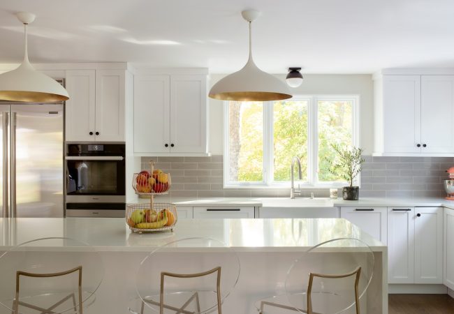 Updated kitchen with sit-down island, built-in cabinets, white finishes, and windows above sink (JM Construction)