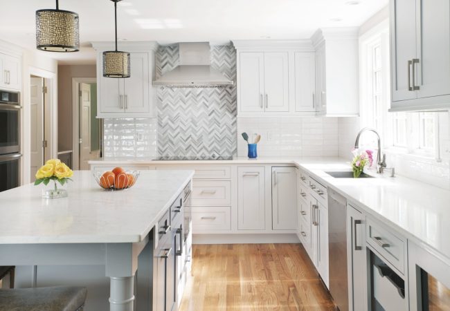Updated kitchen with large island, built-in cabinets, custom tile backsplash, and bright windows (JM Construction)