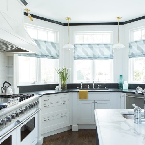 Updated kitchen with island prep sink, large cooktop and hood, and three windows for natural light (JM Construction)