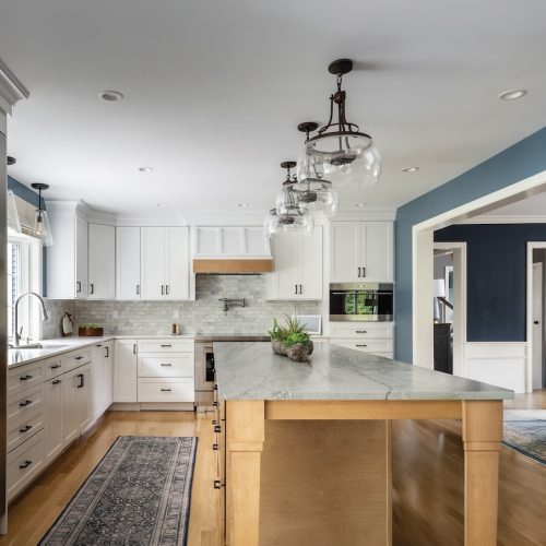 Updated kitchen with large sit-down island, wraparound cabinets, dining area, and tall fridge (JM Construction)